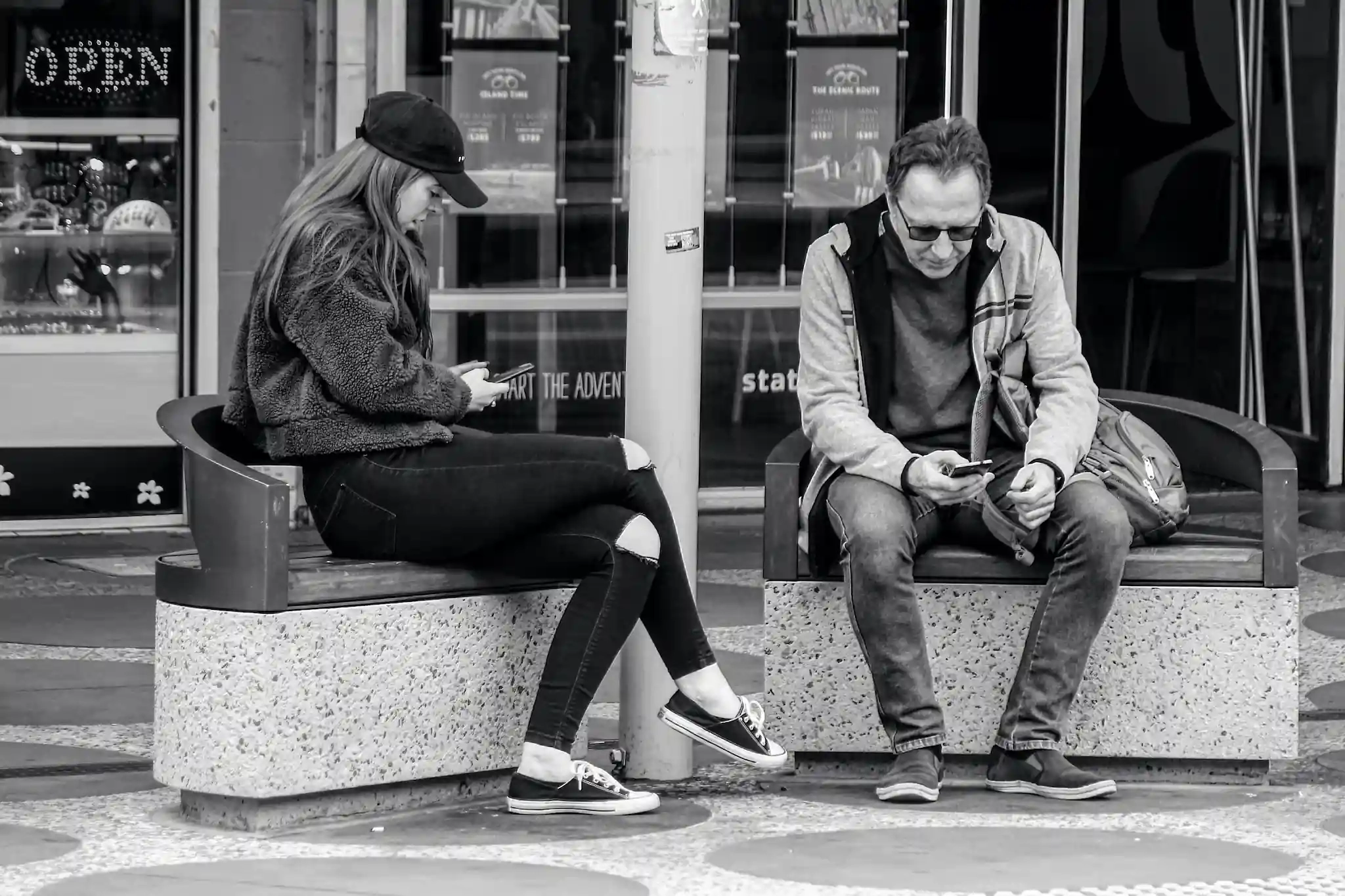 Two people scroll on their smartphones outdoors