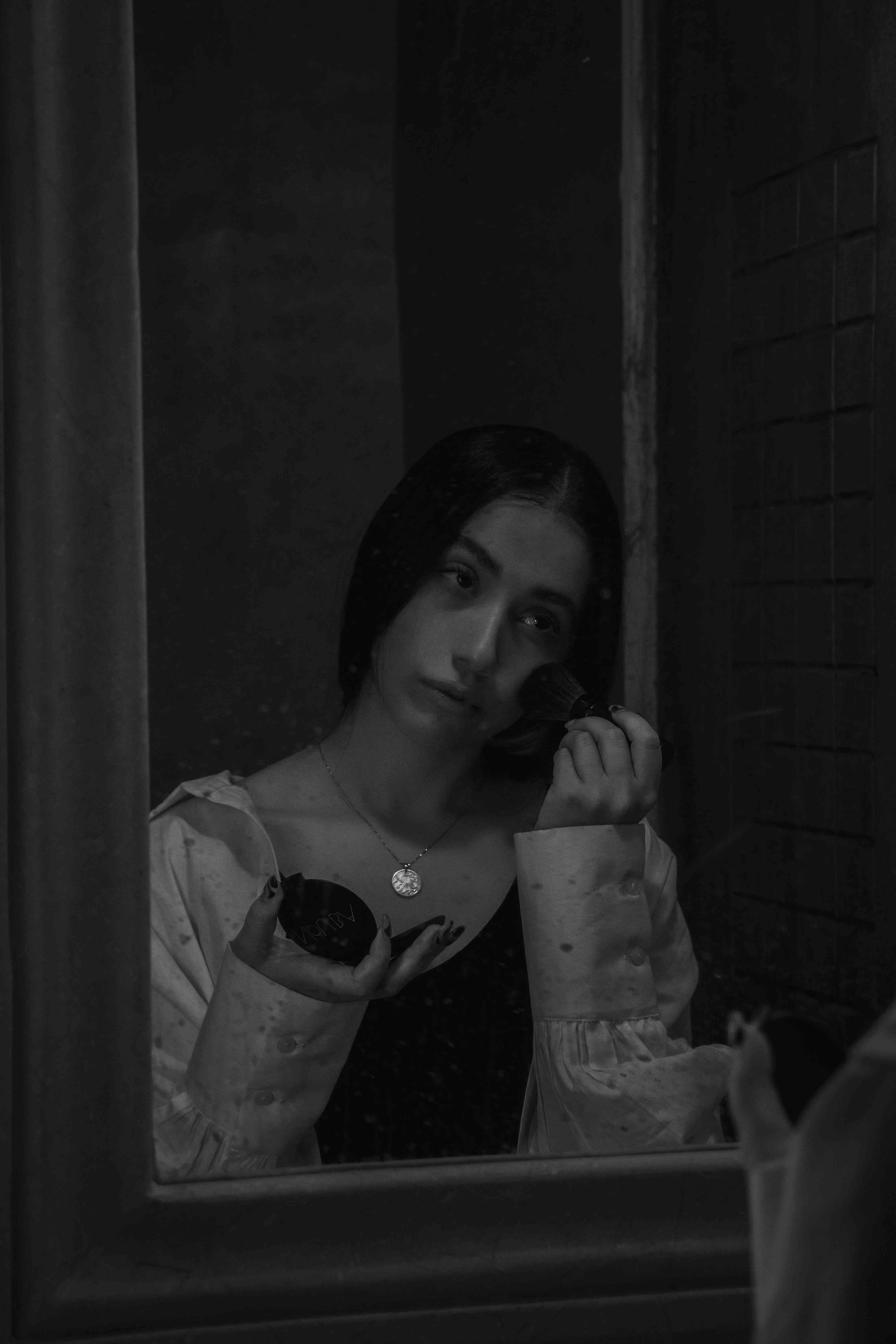 Sad young woman applying makeup.